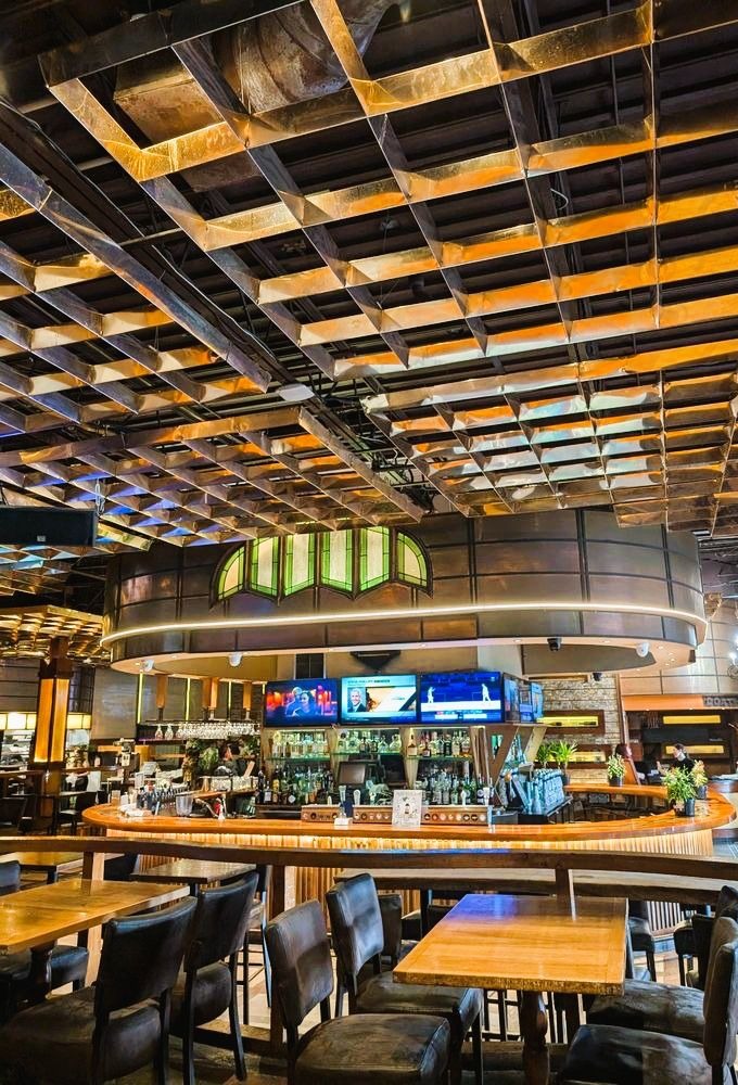 Round bar with a copper grid ceiling and TVs at Arizona Grill Lounge in Etobicoke
