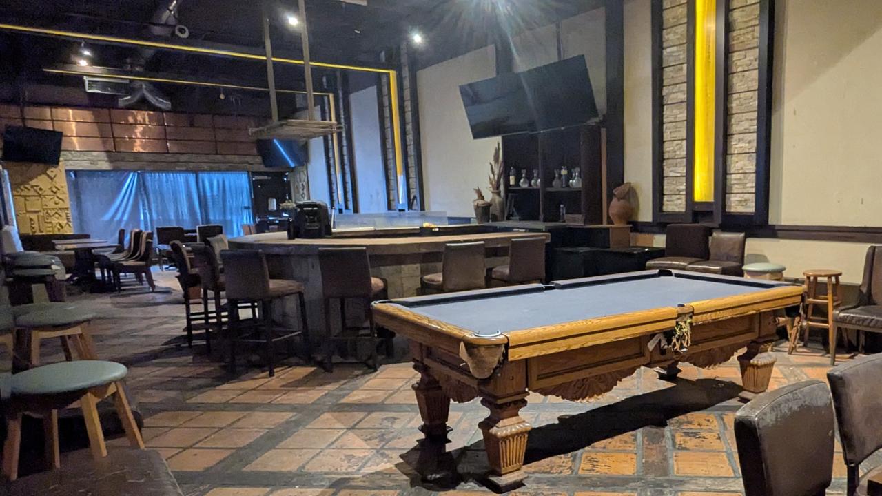 Pool table in a private room at Arizona Grill Lounge, with bar stools and TVs along the wall